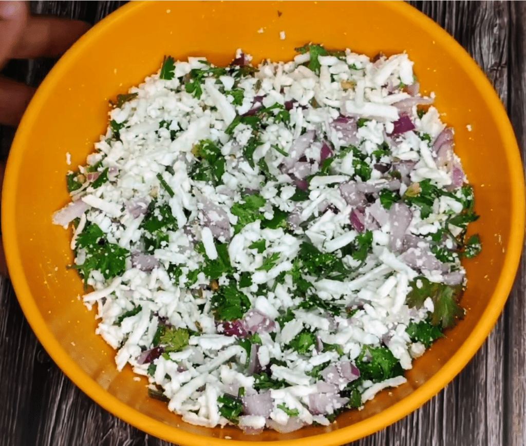 grated paneer mixed with onion, chilli, coriander, cumin, and salt in a bowl