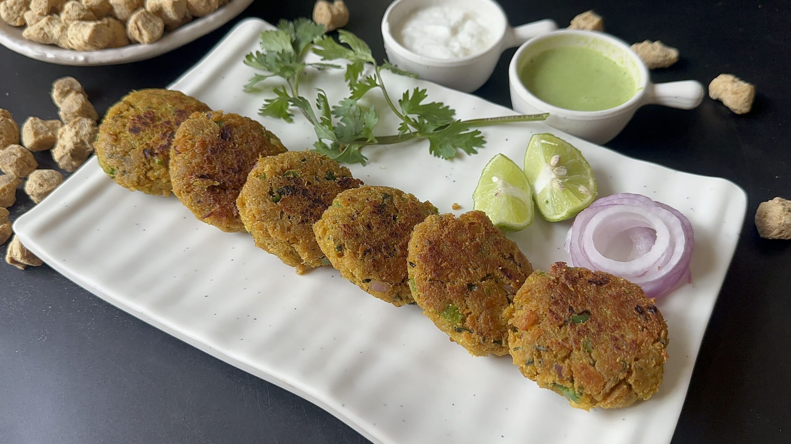 Crispy golden brown soya chunks veg kebabs served hot with green mint chutney, onions, and lemon