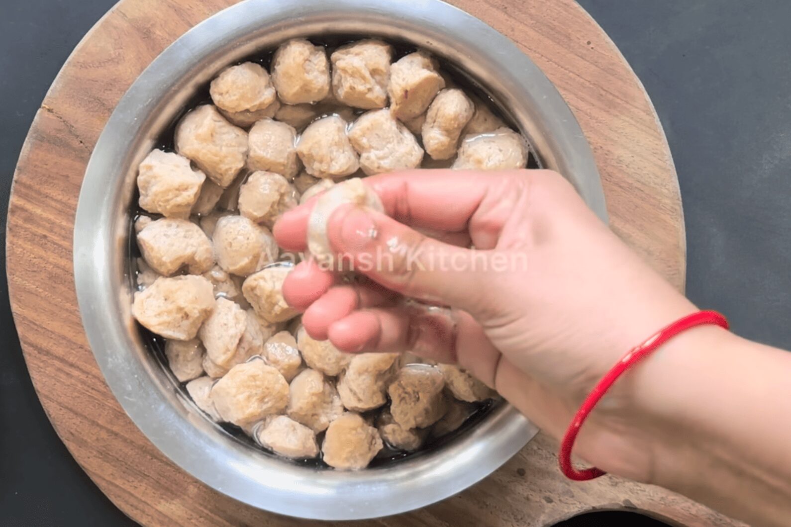 Squeezing excess water out of boiled soya chunks using hands