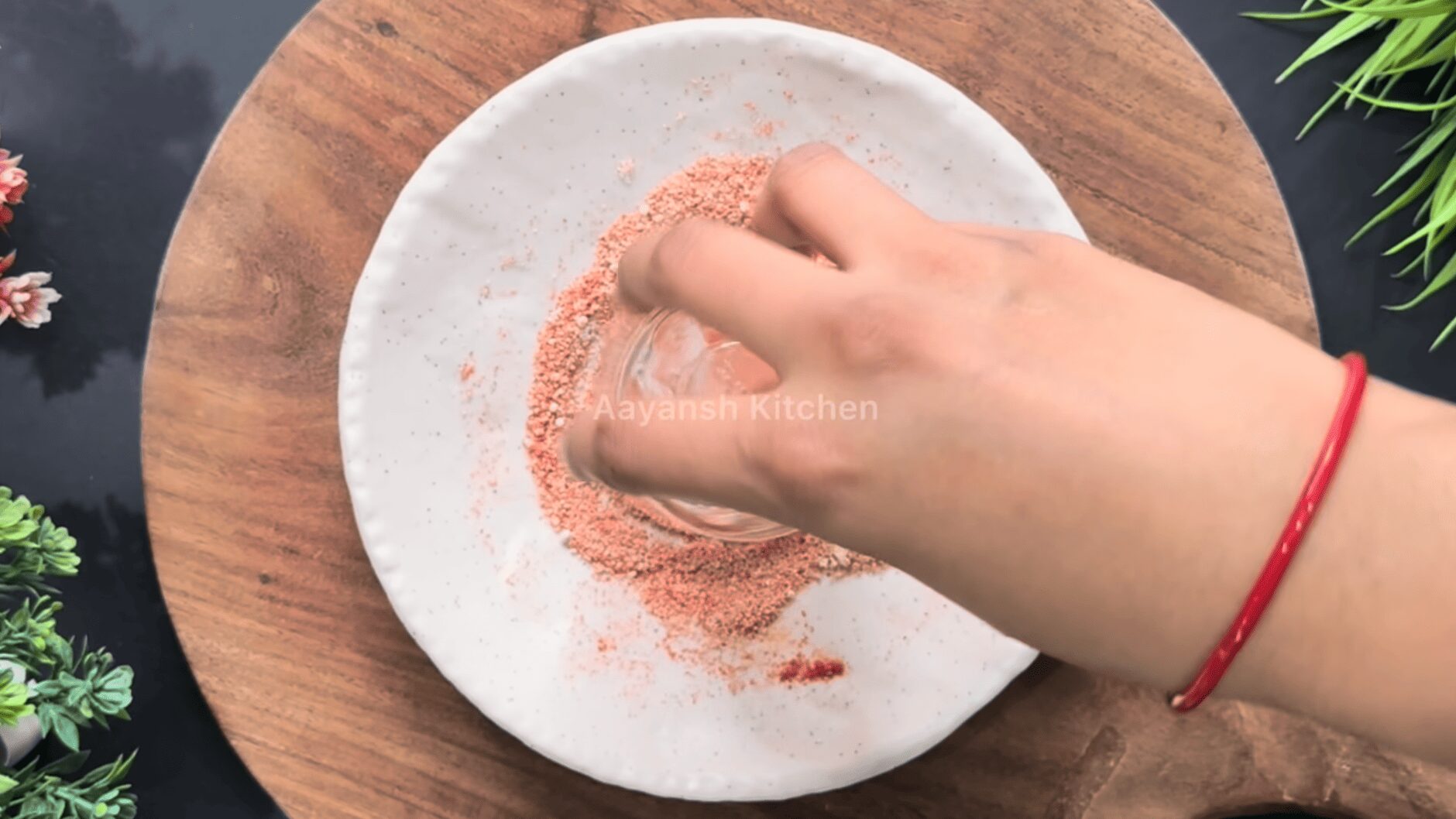 Rim of a small shot glass being rubbed with a lemon wedge and dipped into the spice mixture