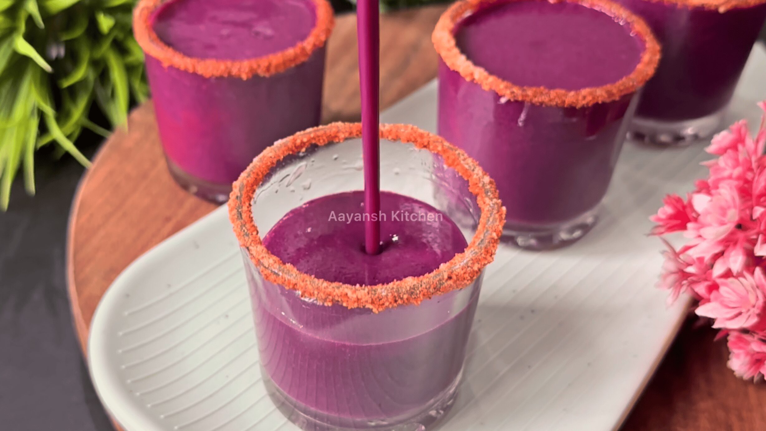 Thick, vibrant purple icy jamun slush being poured into spice-rimmed shot glasses, ready to serve cold